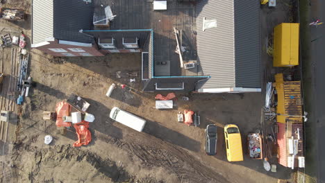 antena de arriba hacia abajo de un trabajador de la construcción con carretilla caminando en el lugar de la construcción - colocación de drones