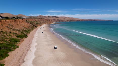 A-drone-view-of-a-camper-van-driving-on-a-white-sand-beach-in-South-Australia