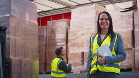 retrato de la gerente de transporte de mercancías femenina en alta visibilidad con tableta digital por el camión que se carga