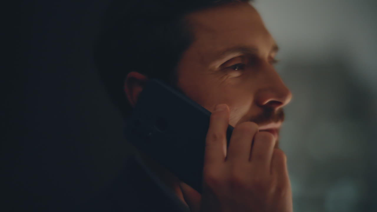 Smiling businessman speaking cellphone standing evening panoramic window closeup