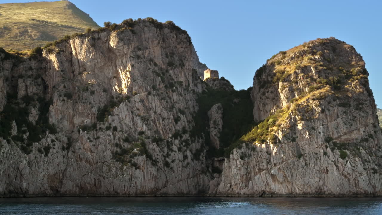 Vista della costa tirrenica in Italia. Alte scogliere, vegetazione, forte in cima a una scogliera
