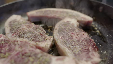 juicy spiced lamb chops frying in pan with steam rising, closeup