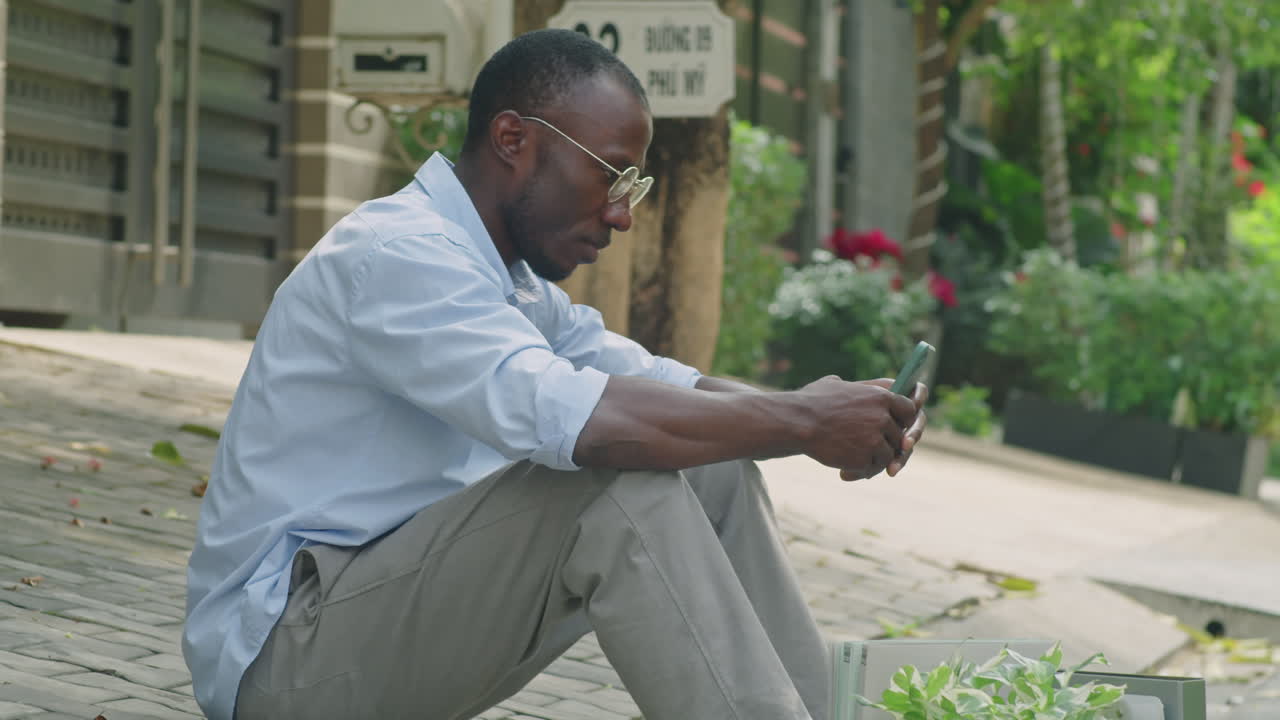 Black Businessman Sitting on Street after Being Fired