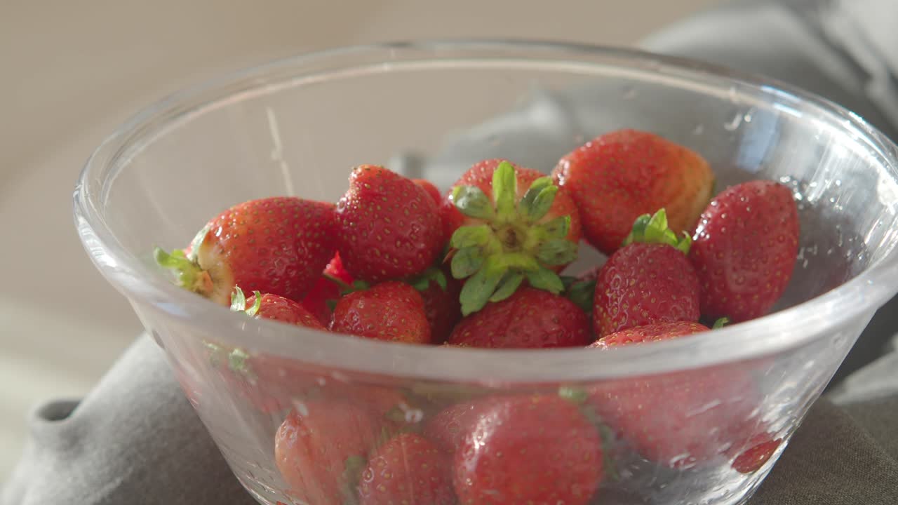 Hand picking a strawberry from a bowl of fresh strawberries