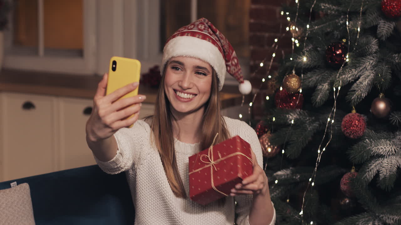 Woman taking Christmas selfie with gift