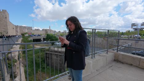 tourist texting on mobile phone at historic landmark in jerusalem. slow motion.
