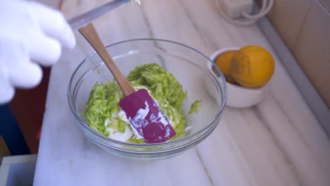 close up on caucasian woman's hands, crushing garlic with vintage tool in a glass bowl, preparing traditional greek , yogurt based dip tzatziki 4k
