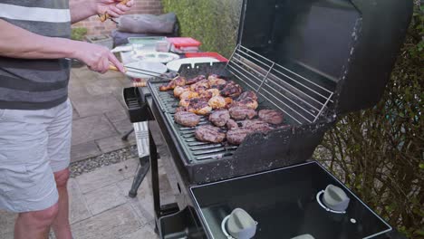 unrecognizable man cooks delicious chicken thigh and sausages on barbecue grill