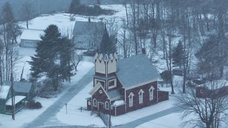 wide aerial around swedish lutheran church in monson in snow blizzard