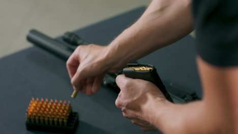 primer plano de manos masculinas cargando balas en un cargador de armas en un campo de tiro