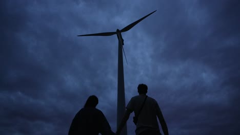 moving storm clouds time-lapse, couple holding hands next to wind turbine