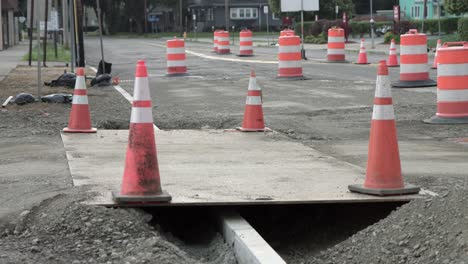 conos de tráfico naranja y barreras de barril - conos de seguridad cuidadosamente colocados en el agujero de la carretera