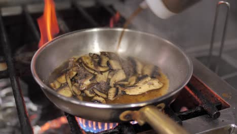 adding soy sauce to champignon mushroom frying on pan, close up