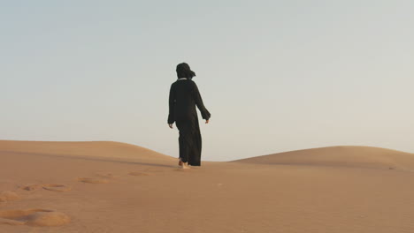 Sígueme-Foto-De-Una-Hermosa-Mujer-Musulmana-Con-Hijab-Caminando-Descalza-En-Un-Desierto-Ventoso