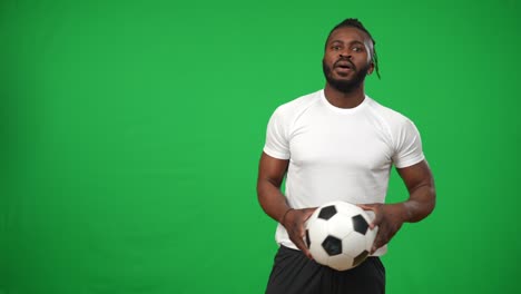professional african american footballer juggling ball on green screen and looking at camera. portrait of serious confident concentrated sportsman posing at chromakey background.