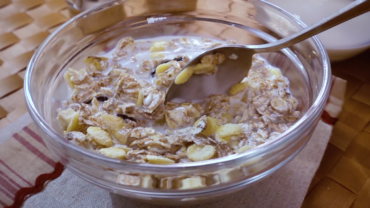 muesli de cereales de grano entero en un tazón para un delicioso desayuno matutino con leche. cámara lenta con toma de seguimiento de rotación.