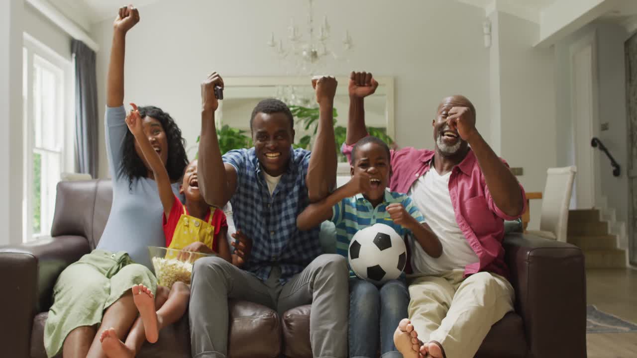 feliz familia afroamericana animando mientras veían el partido en la televisión