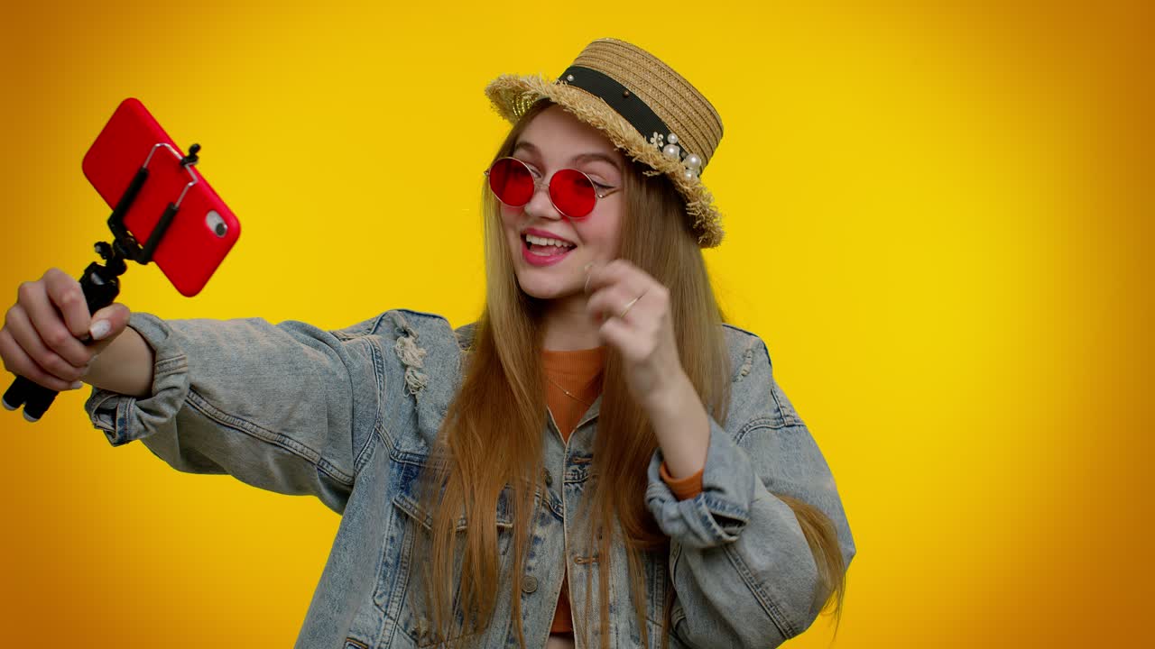 blogger viajera con gafas de sol, tomando selfies en el teléfono móvil, comunicándose por video llamada en línea