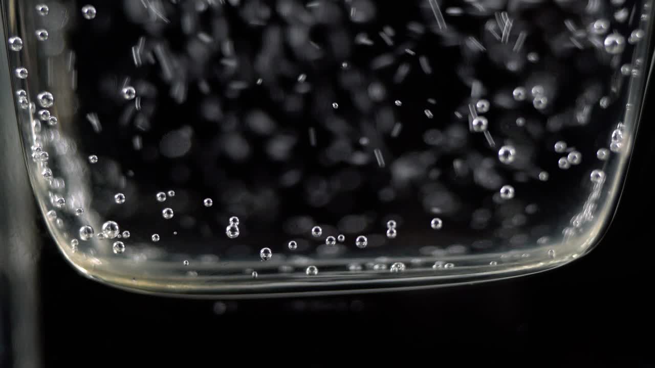 유리잔에 미네랄 워터 거품의 근접. 어두운 배경에 산소 공을 가진 탄산 신선한 스파클링 음료의 매크로 상점