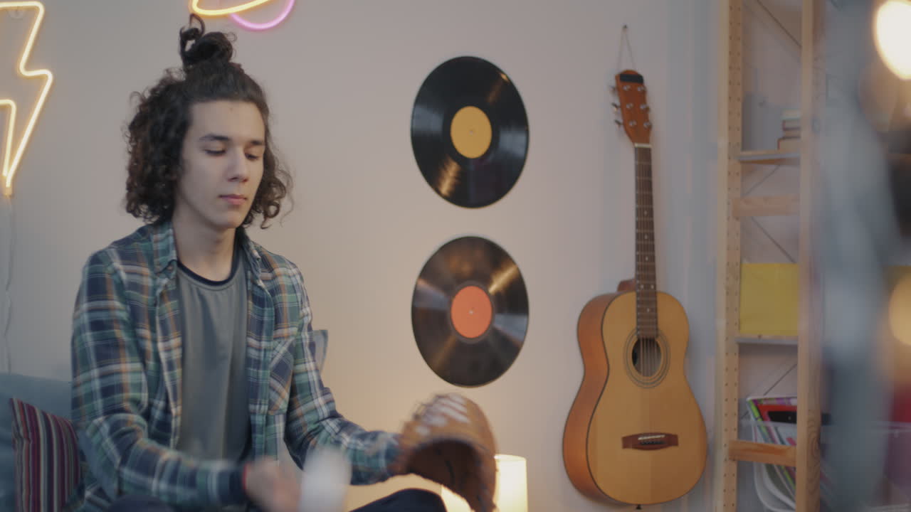 Teenage Boy Relaxing in His Bedroom with Baseball Gear