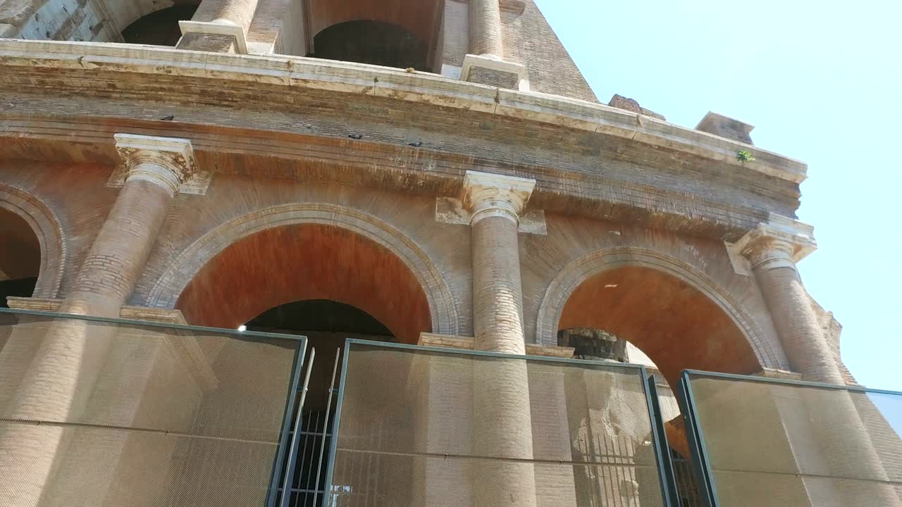 Tilt of ruins of the colosseum in Rome, Italy against blue sky