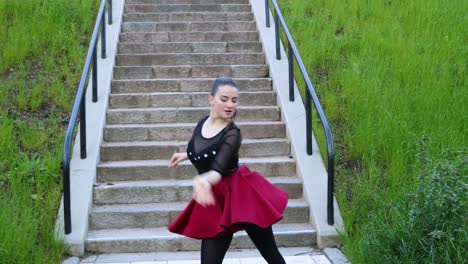 beautiful female dancer does a dance routine outside next to the stairs