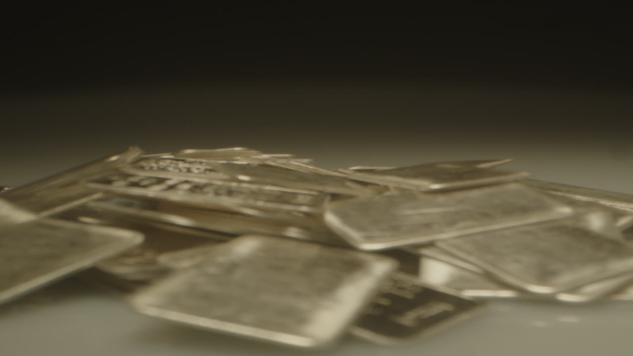 Beautiful macro dolly out of a pile of shiny silver plates in a well lit studio