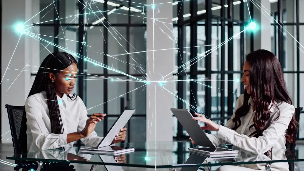 High-angle video of two professionals using tablets at a glass table, overlaid with digital network