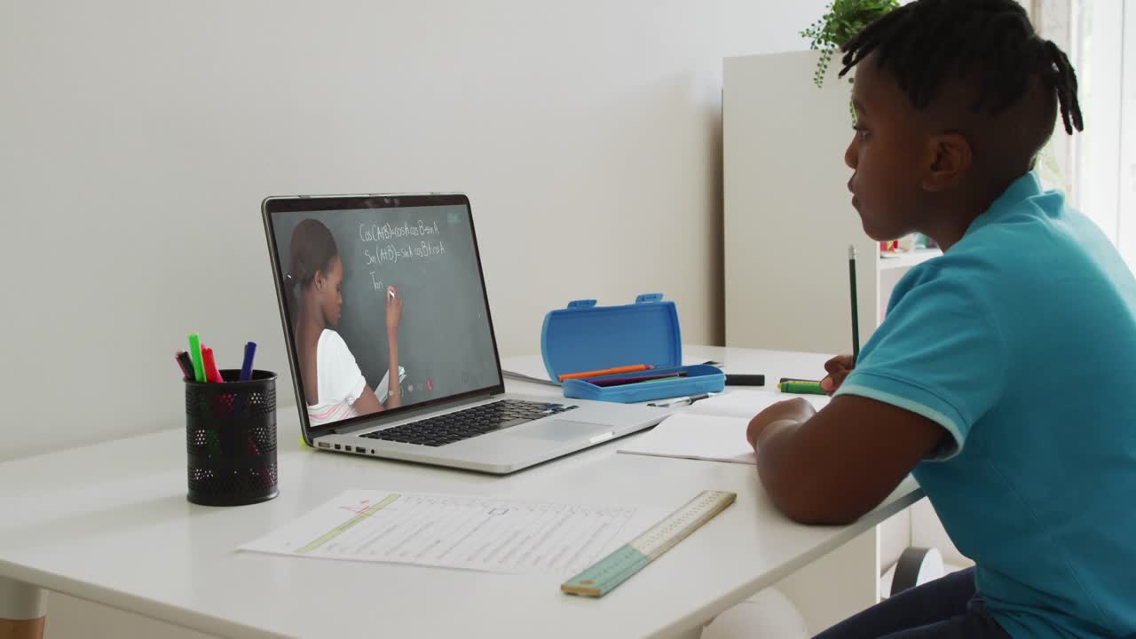 African american boy having a video call on laptop while doing homework at home