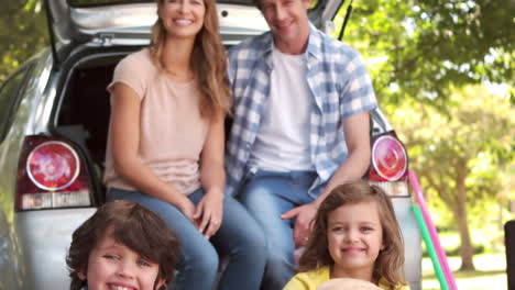 family with dog sitting in car trunk