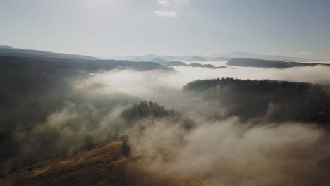 Vista-Aérea-De-Una-Vasta-Tierra-De-Color-Dorado-Envuelta-En-Niebla,-Alejándose-Del-Tiro