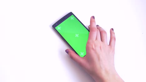 hand taking smart phone with green chroma screen from white table closeup