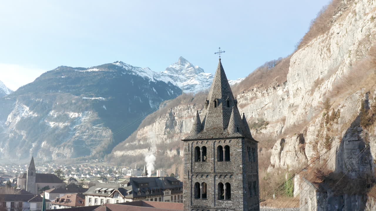 목가적인 작은 마을의 아름다운 오래된 교회 탑에서 날아가는 드론