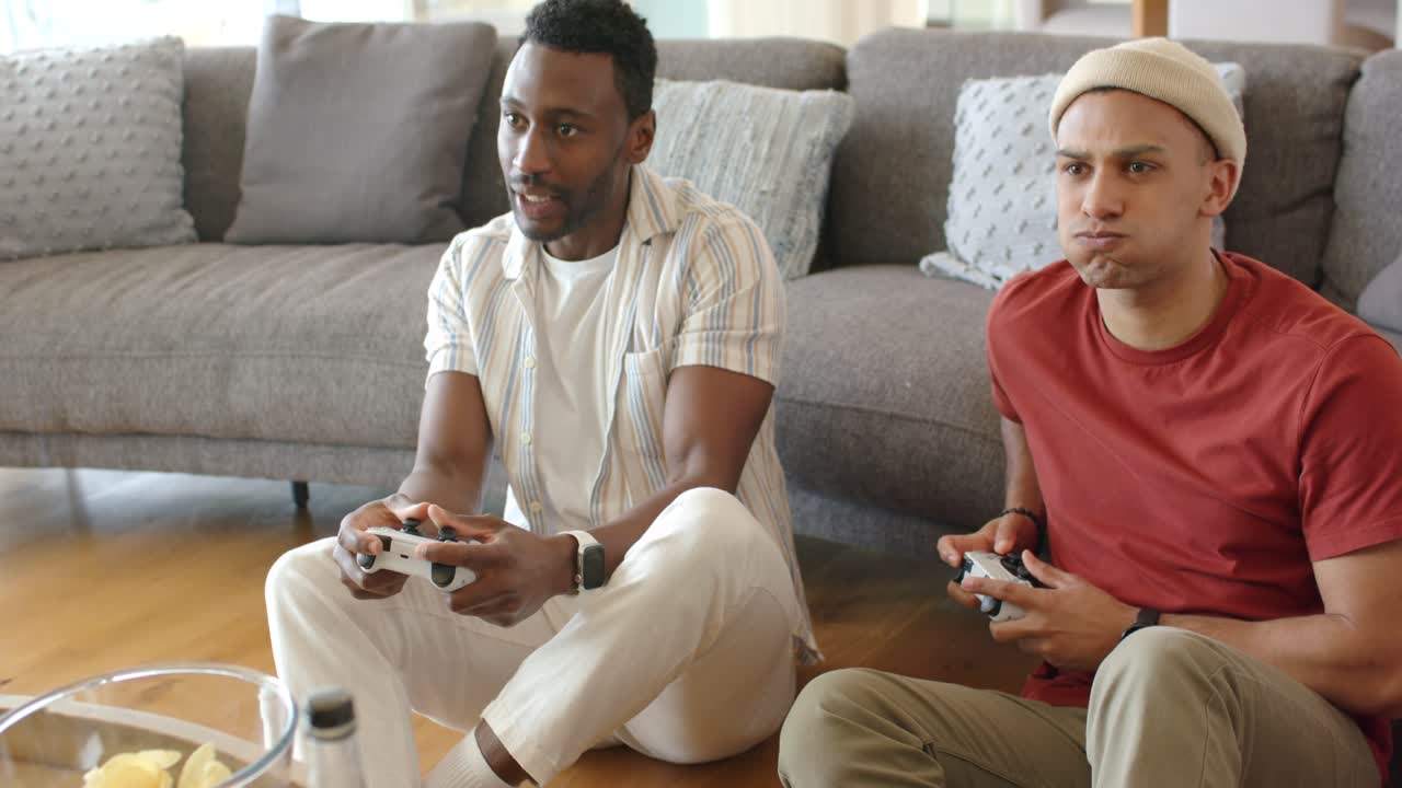 Diverse male friends picking up wireless controllers, pressing buttons to compete in living room