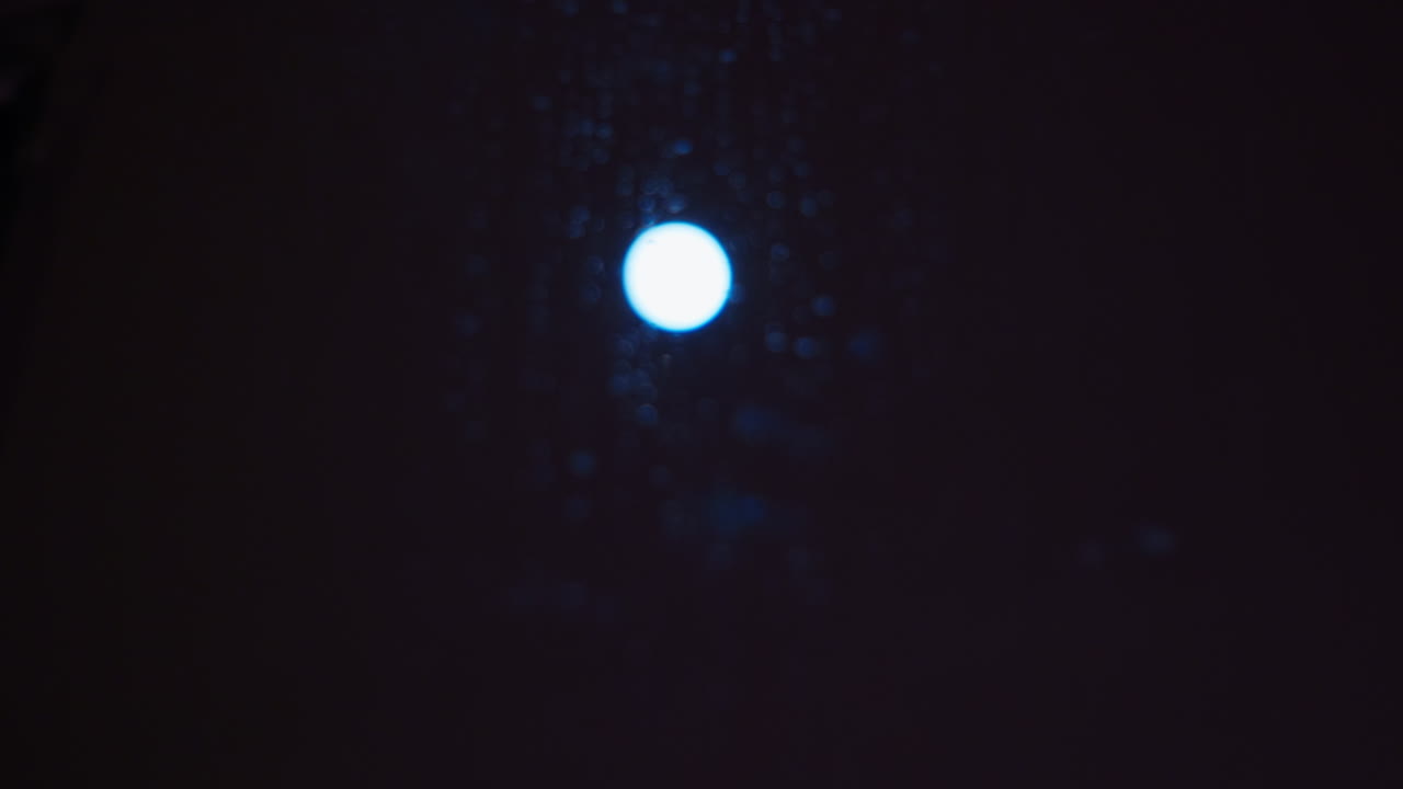 La luna splende luminosa in una notte fredda e buia e mostra l'acqua che gocciola sulla finestra.