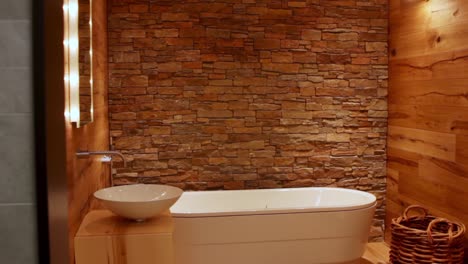 wide shot of a cosy bathroom with an all wooden floor and brick stone wall