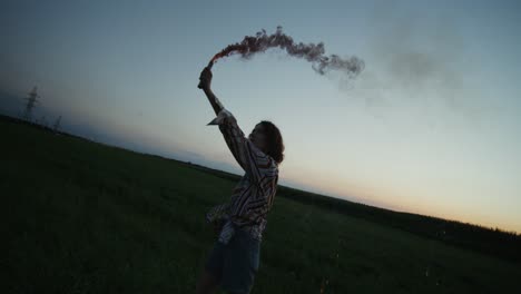 woman in field with pink smoke