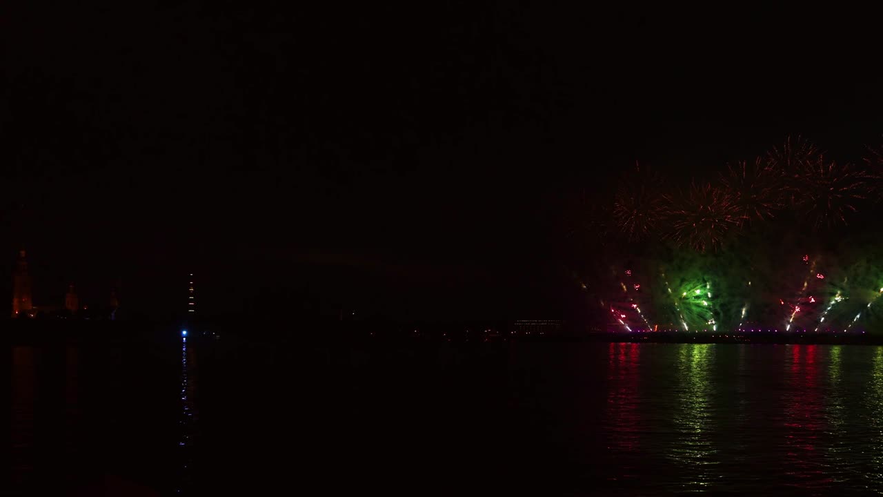 어두운 하늘에서 화려한 반사와 함께 화려한 불꽃놀이와 밝은 빛이 물 속에 아름답게 반사됩니다.