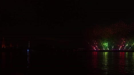fuegos artificiales coloridos festivos e iluminación en el cielo oscuro con un hermoso reflejo en el agua. velas escarlata de vacaciones