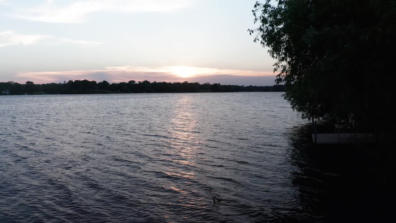 일몰 동안 호숫가를 따라 낮고 느린 공중 돌리 샷