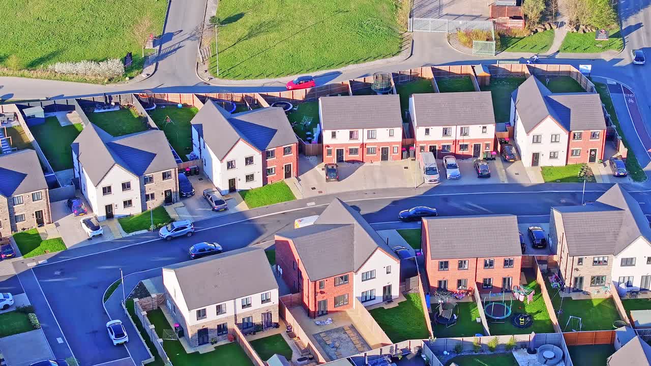 Revealing modern homes with private gardens, fences and parked cars in a planned residential area in Manvers, Rotherham, South Yorkshire, drone real time ascending