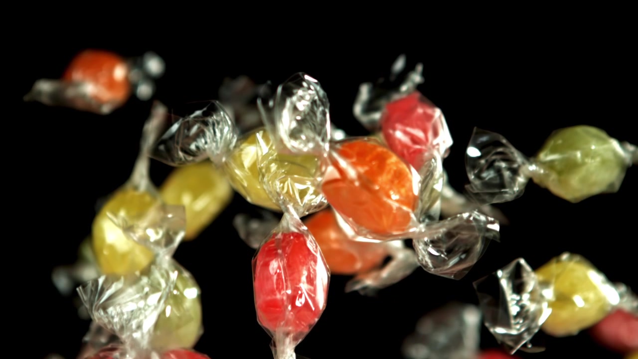 Doces Embrulhados Vibrantes Flutuando em Câmera Lenta Contra Fundo Preto