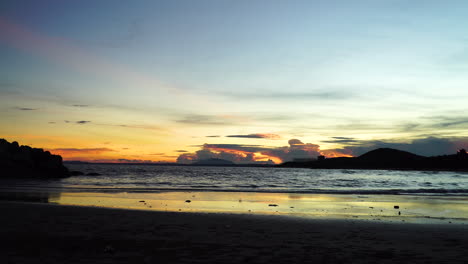 Mareas-Tranquilas-Que-Se-Estrellan-En-La-Orilla-De-La-Playa-Al-Atardecer,-Colorido-Naranja,-Rosa,-Cielo-Azul