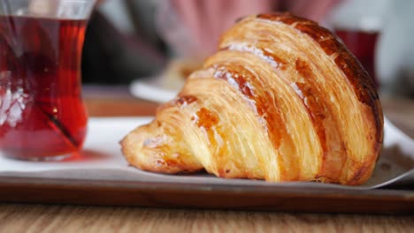 primer plano de un croissant recién horneado en una bandeja con té