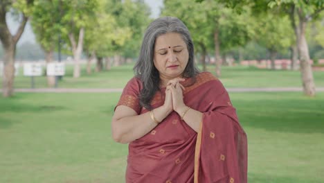 religious indian old woman praying in park