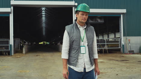 supervisor holding clipboard making notes at modern livestock cowshed alone.