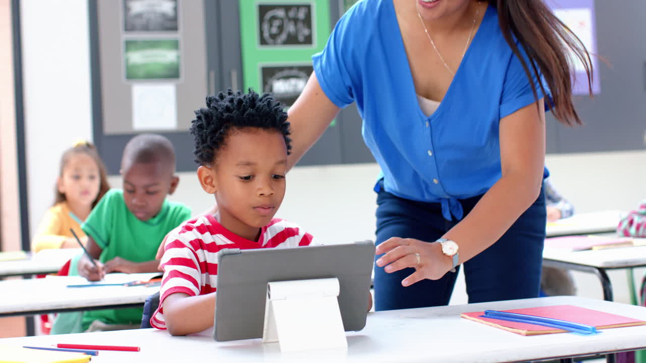 In school, teacher helping student using tablet in classroom, engaging in learning