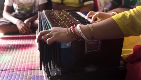 married indian teacher playing music with harmonium at classroom, students learning music, unrecognizable