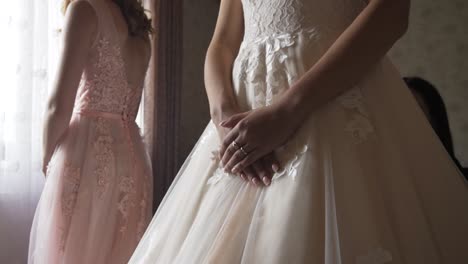 cerca de la novia sosteniendo las manos sobre el vestido vintage y la dama de honor de pie