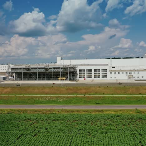 industrial plant on green field. huge territory with white buildings against blue sky. exterior of factory in nature. aerial view.